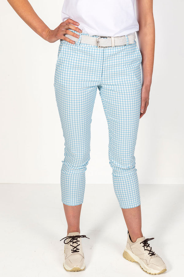 Woman in white golf polo shirt and pale blue and white gingham golf trousers