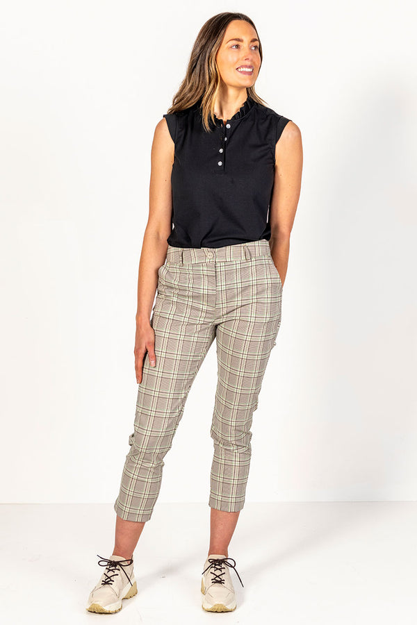 Woman wearing a black sleeveless top and green, stone and black plaid golf  pants 