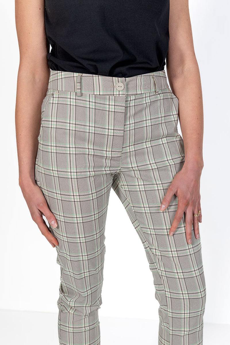 Woman wearing green,stone and black plaid golf pants on a white background