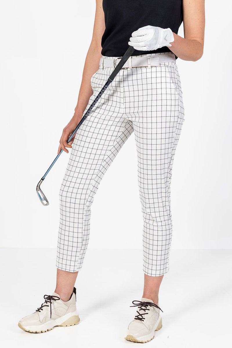 Woman in white and black window pane check golf  pants holding a golf club