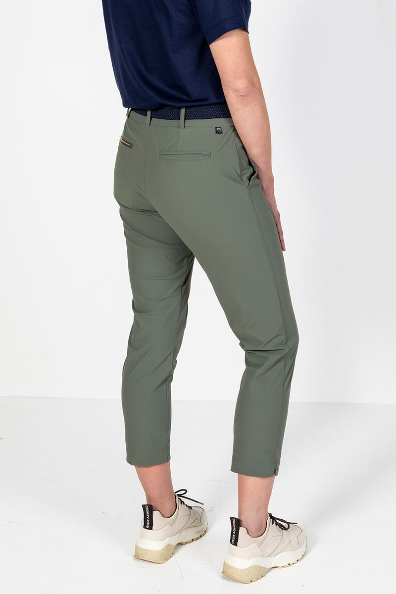 Woman wearing a navy golf polo shirt and olive lightweight golf pants on a white background