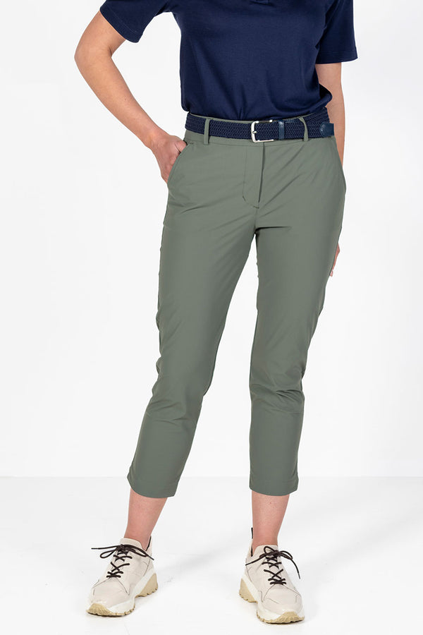 Woman wearing a navy golf polo shirt and olive lightweight golf pants on a white background